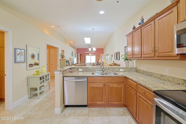 kitchen featuring light stone countertops, lofted ceiling with skylight, sink, and stainless steel appliances