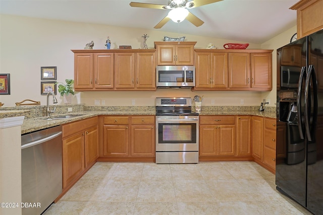 kitchen with sink, lofted ceiling, stainless steel appliances, and light stone counters