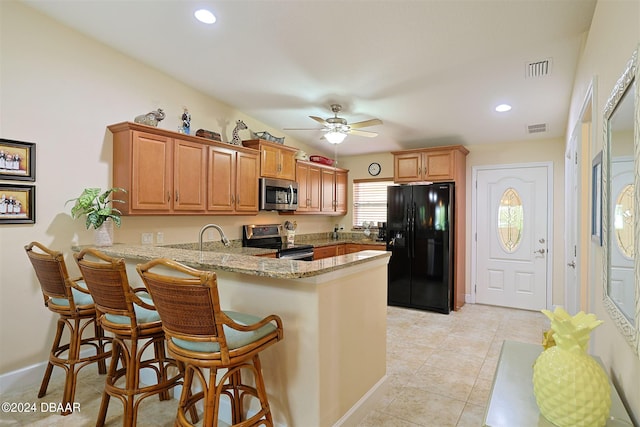 kitchen featuring kitchen peninsula, appliances with stainless steel finishes, light stone countertops, a kitchen breakfast bar, and ceiling fan