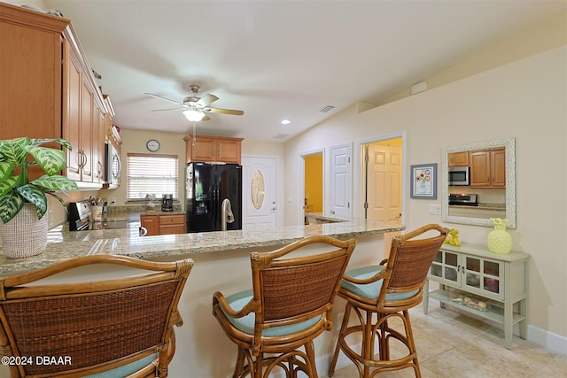 kitchen with vaulted ceiling, kitchen peninsula, light tile patterned floors, and stainless steel appliances