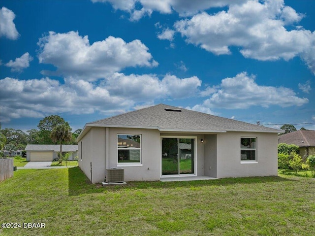 back of house featuring central AC unit, a yard, and a garage