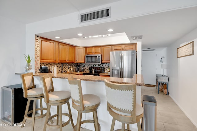 2947 S Atlantic Ave Unit 601, Daytona Beach, FL 32118 - kitchen with stainless steel appliances, a peninsula, backsplash, light stone counters, and a kitchen breakfast bar