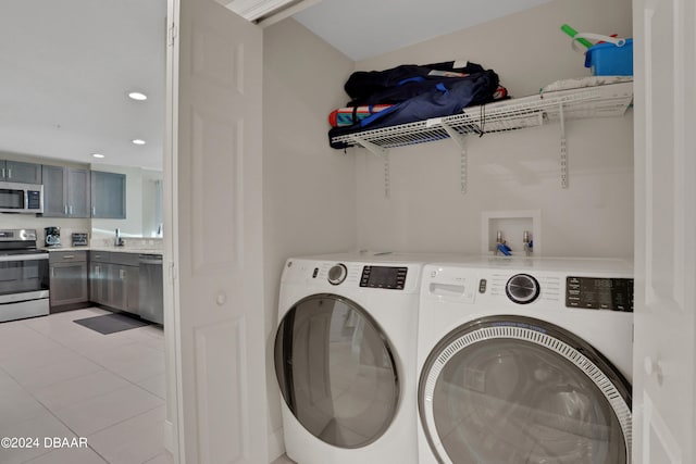 laundry area with washing machine and clothes dryer and light tile patterned floors