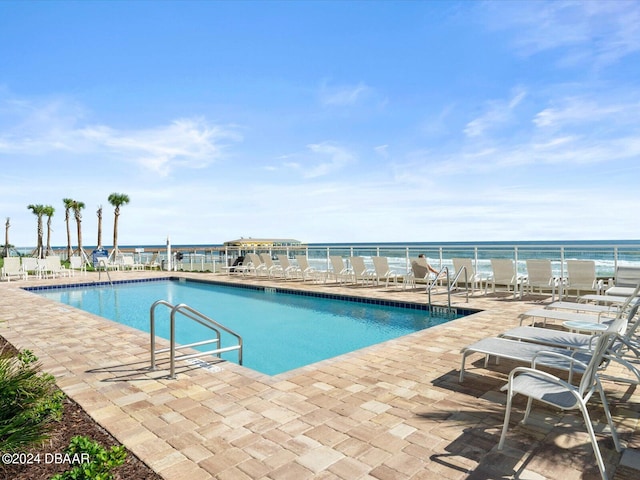 view of pool featuring a patio and a water view