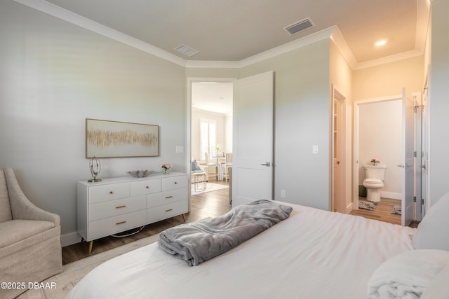 bedroom with light hardwood / wood-style floors, ensuite bath, and crown molding