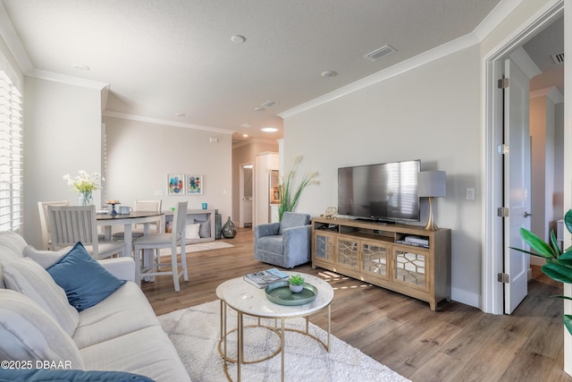 living room with plenty of natural light, light hardwood / wood-style floors, and crown molding