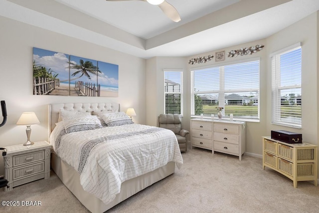 bedroom featuring ceiling fan, a tray ceiling, and light colored carpet