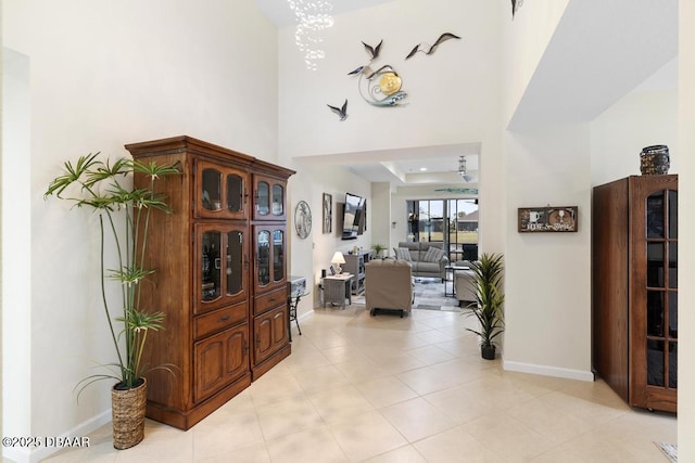 hallway with a raised ceiling and light tile patterned flooring