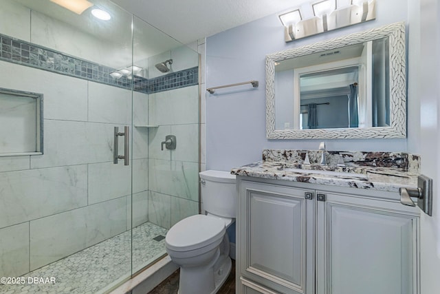 bathroom featuring toilet, vanity, and a shower with door