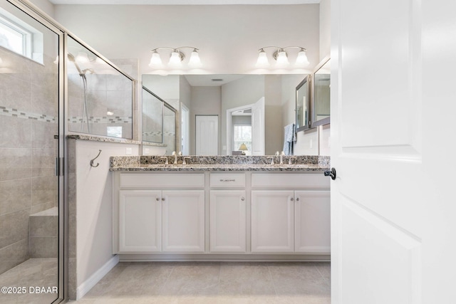 bathroom with a stall shower, tile patterned floors, a sink, and double vanity