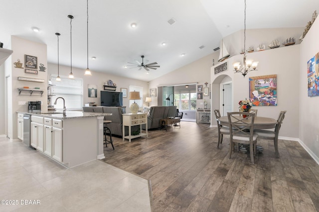 dining space with visible vents, arched walkways, wood finished floors, high vaulted ceiling, and ceiling fan with notable chandelier