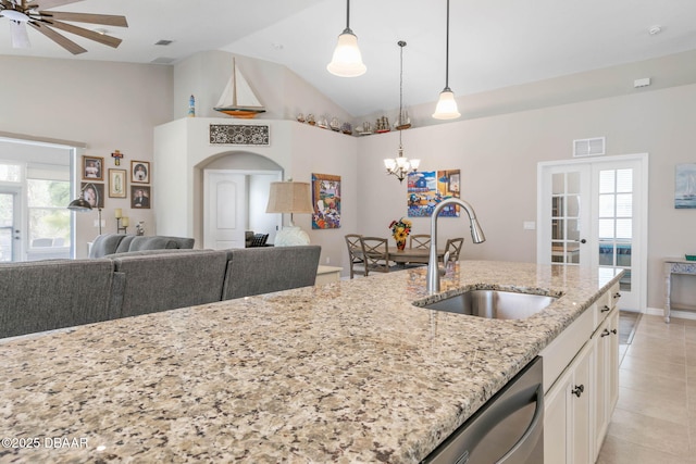 kitchen with light tile patterned floors, open floor plan, white cabinetry, a sink, and dishwasher