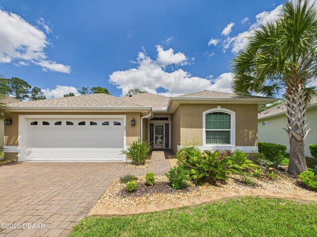 63 Park Place Cir, Palm Coast, FL 32164 - view of front of home with stucco siding, a garage, decorative driveway, and a shingled roof