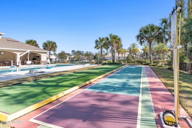 view of community featuring fence, a swimming pool, and shuffleboard