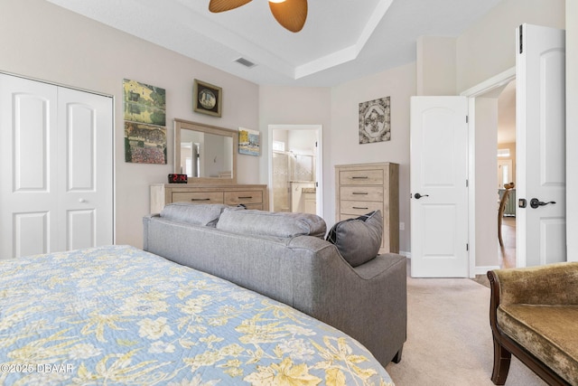 bedroom with light carpet, visible vents, a ceiling fan, a closet, and a tray ceiling