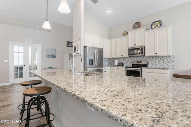 kitchen with french doors, stainless steel appliances, decorative backsplash, white cabinets, and a sink