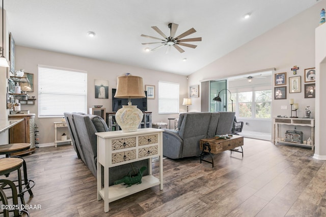 living area with vaulted ceiling, ceiling fan, wood finished floors, and baseboards