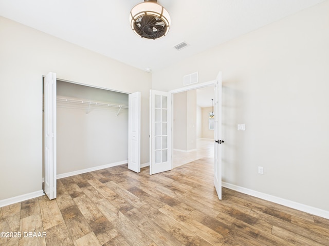 63 Park Place Cir, Palm Coast, FL 32164 - unfurnished bedroom with french doors, wood finished floors, a closet, and baseboards
