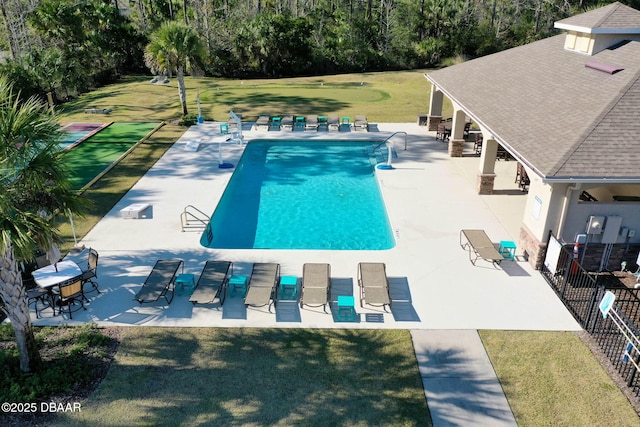 pool with a patio area, fence, and a yard