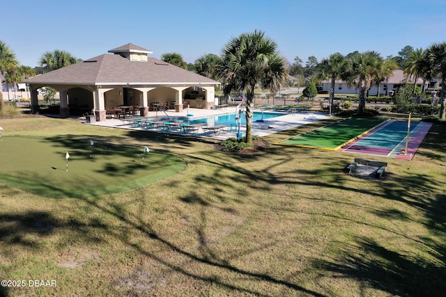 community pool with a patio area, a yard, and fence