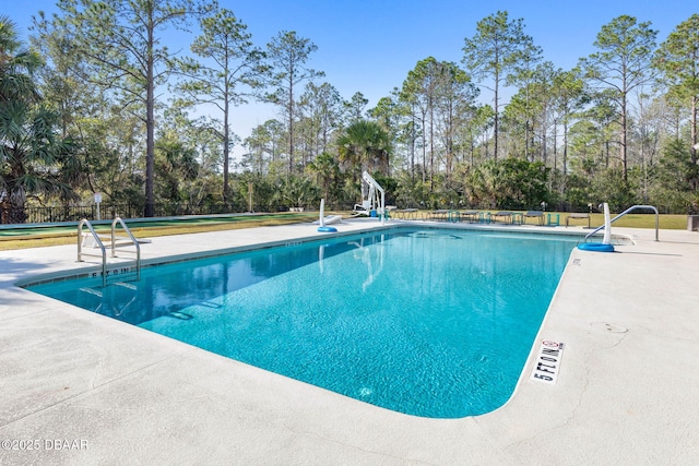 pool with a patio area and fence