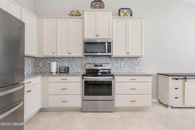 kitchen featuring white cabinets, appliances with stainless steel finishes, light stone counters, and backsplash