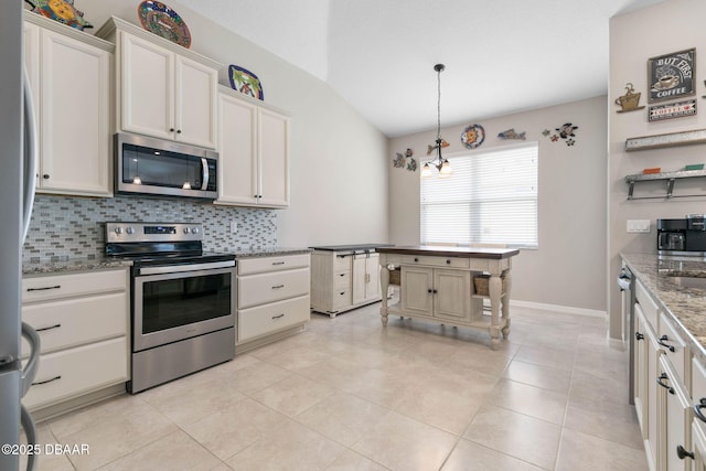 kitchen with light tile patterned floors, light stone counters, stainless steel appliances, white cabinetry, and backsplash