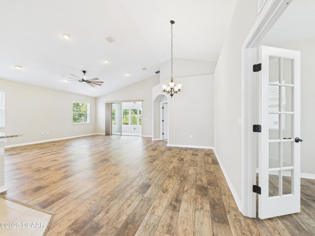 63 Park Place Cir, Palm Coast, FL 32164 - unfurnished living room featuring arched walkways, wood finished floors, lofted ceiling, a ceiling fan, and baseboards
