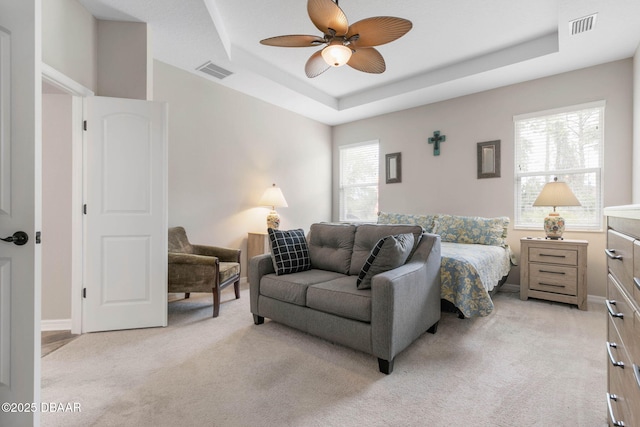 bedroom featuring a raised ceiling, visible vents, and light carpet