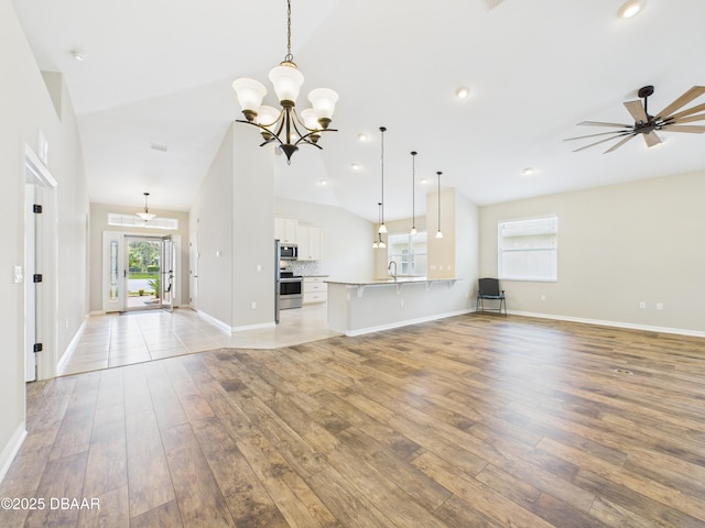63 Park Place Cir, Palm Coast, FL 32164 - unfurnished living room featuring light wood-style floors, lofted ceiling, baseboards, a sink, and a chandelier