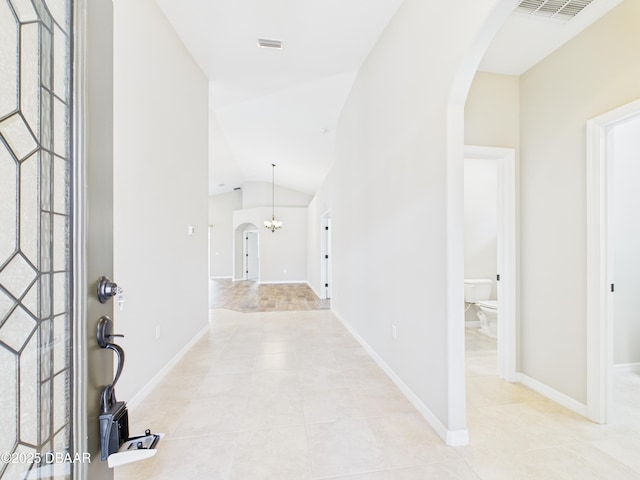 63 Park Place Cir, Palm Coast, FL 32164 - entryway featuring arched walkways, light tile patterned flooring, vaulted ceiling, a chandelier, and baseboards