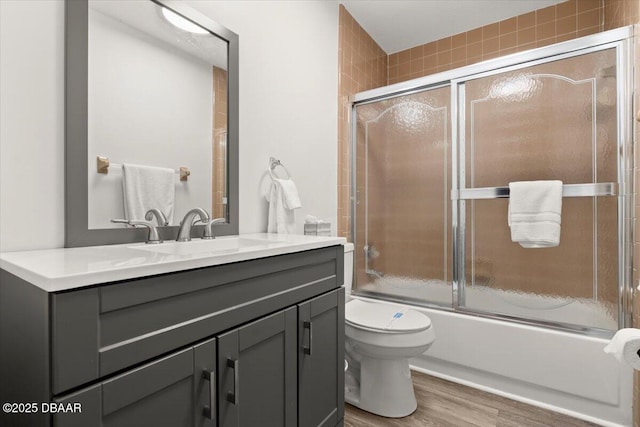 full bathroom featuring toilet, vanity, combined bath / shower with glass door, and hardwood / wood-style floors