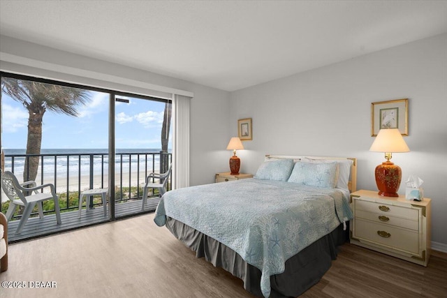 bedroom with a beach view, wood-type flooring, a water view, and access to exterior