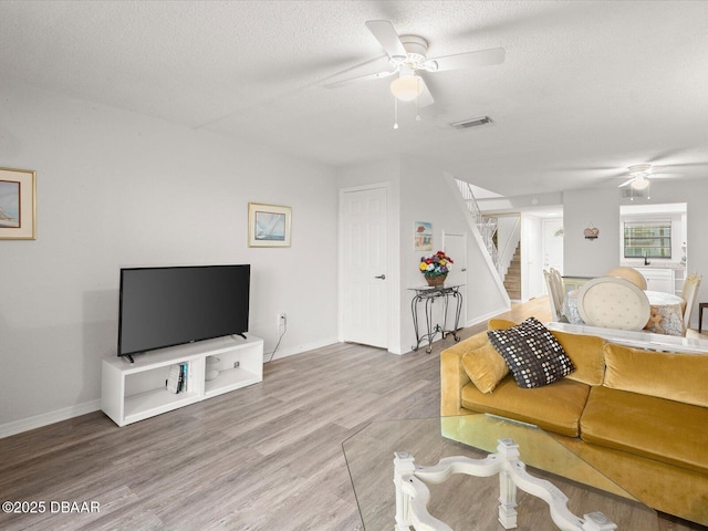 living room with hardwood / wood-style flooring, a textured ceiling, and ceiling fan