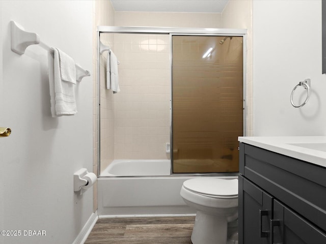 full bathroom with wood-type flooring, toilet, combined bath / shower with glass door, and vanity