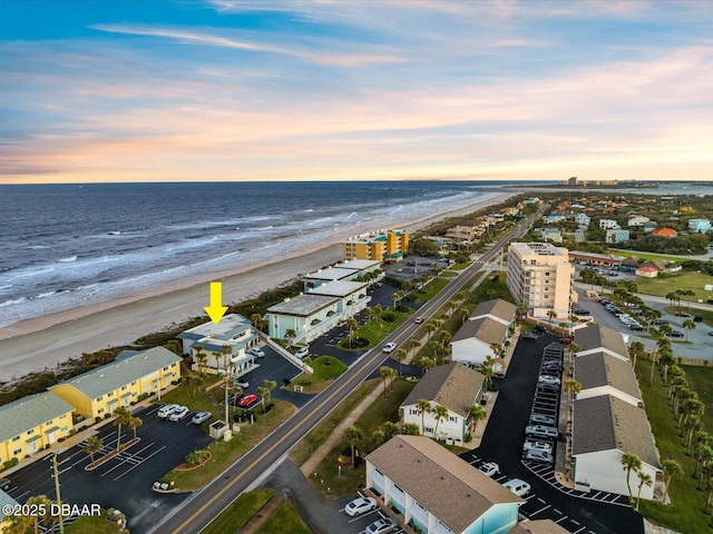 aerial view at dusk with a beach view and a water view