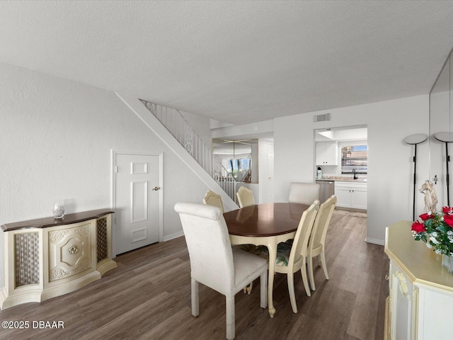 dining space featuring hardwood / wood-style flooring, sink, and a textured ceiling