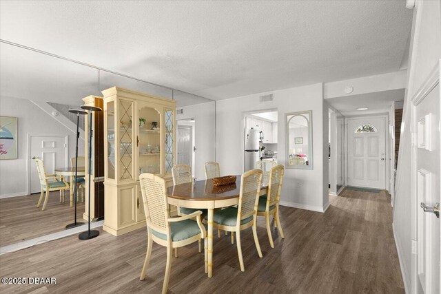 dining space featuring wood-type flooring and a textured ceiling