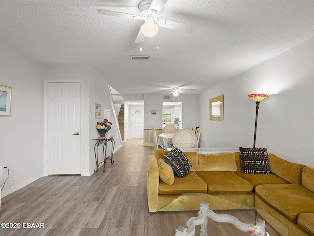 living room with hardwood / wood-style flooring, a textured ceiling, and ceiling fan