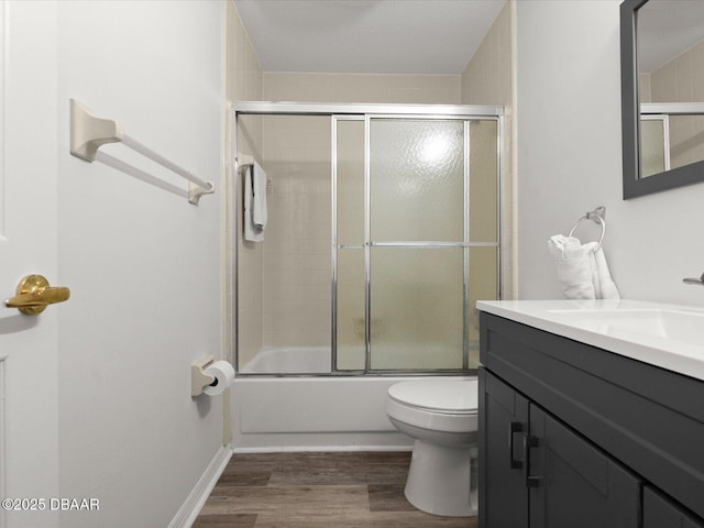 full bathroom featuring wood-type flooring, combined bath / shower with glass door, vanity, and toilet