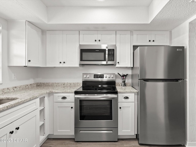 kitchen featuring white cabinetry, appliances with stainless steel finishes, dark hardwood / wood-style flooring, and light stone counters