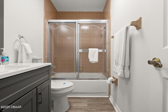 full bathroom with bath / shower combo with glass door, vanity, toilet, and hardwood / wood-style floors