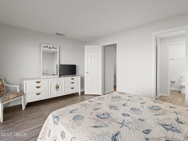 bedroom with dark hardwood / wood-style flooring and ensuite bath