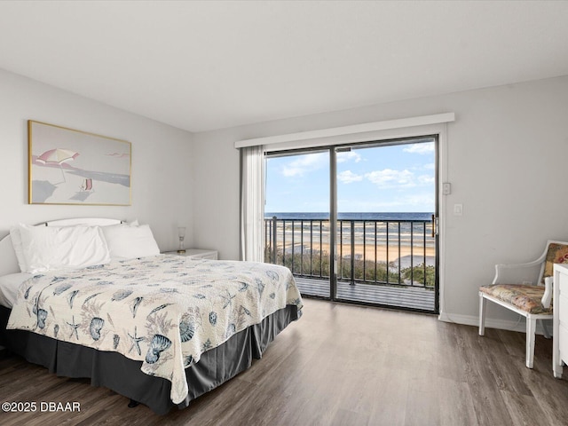 bedroom featuring access to exterior, hardwood / wood-style flooring, and a water view