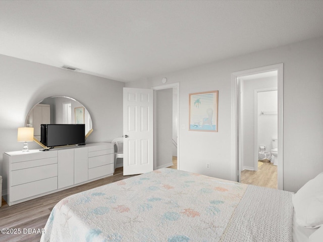 bedroom featuring ensuite bathroom and light hardwood / wood-style flooring