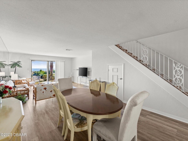 dining space with hardwood / wood-style flooring and a textured ceiling