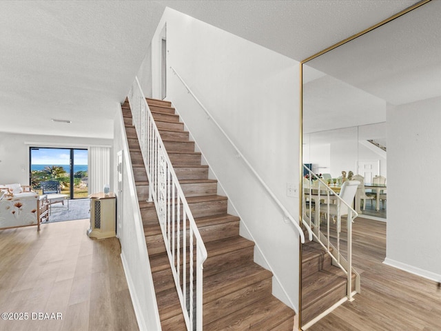 staircase with wood-type flooring and a textured ceiling