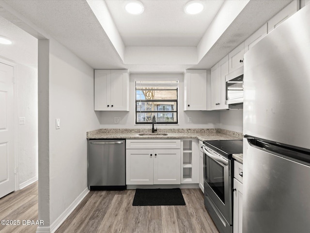 kitchen featuring stainless steel appliances, white cabinetry, a raised ceiling, and sink