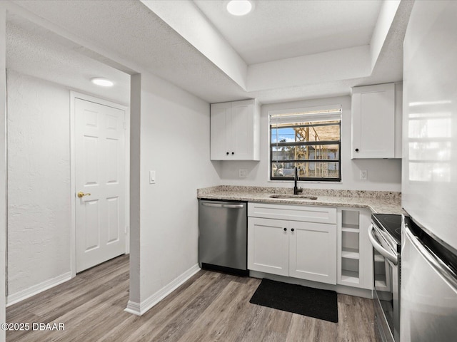 kitchen with white cabinetry, appliances with stainless steel finishes, sink, and light wood-type flooring