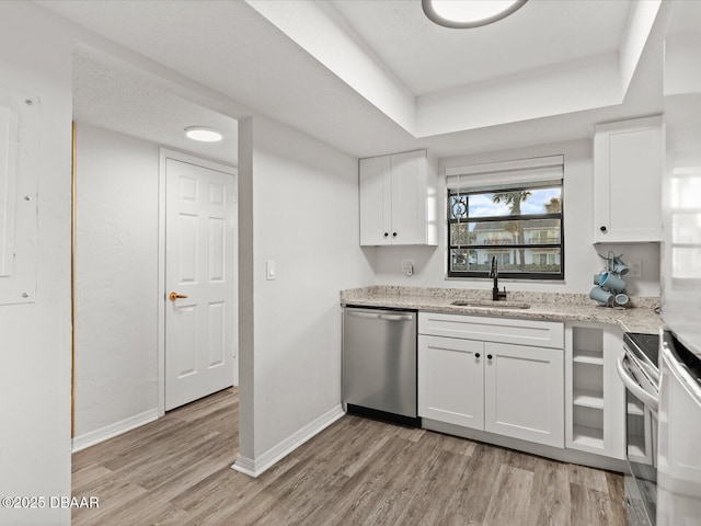 kitchen featuring sink, appliances with stainless steel finishes, white cabinetry, light stone counters, and light hardwood / wood-style floors